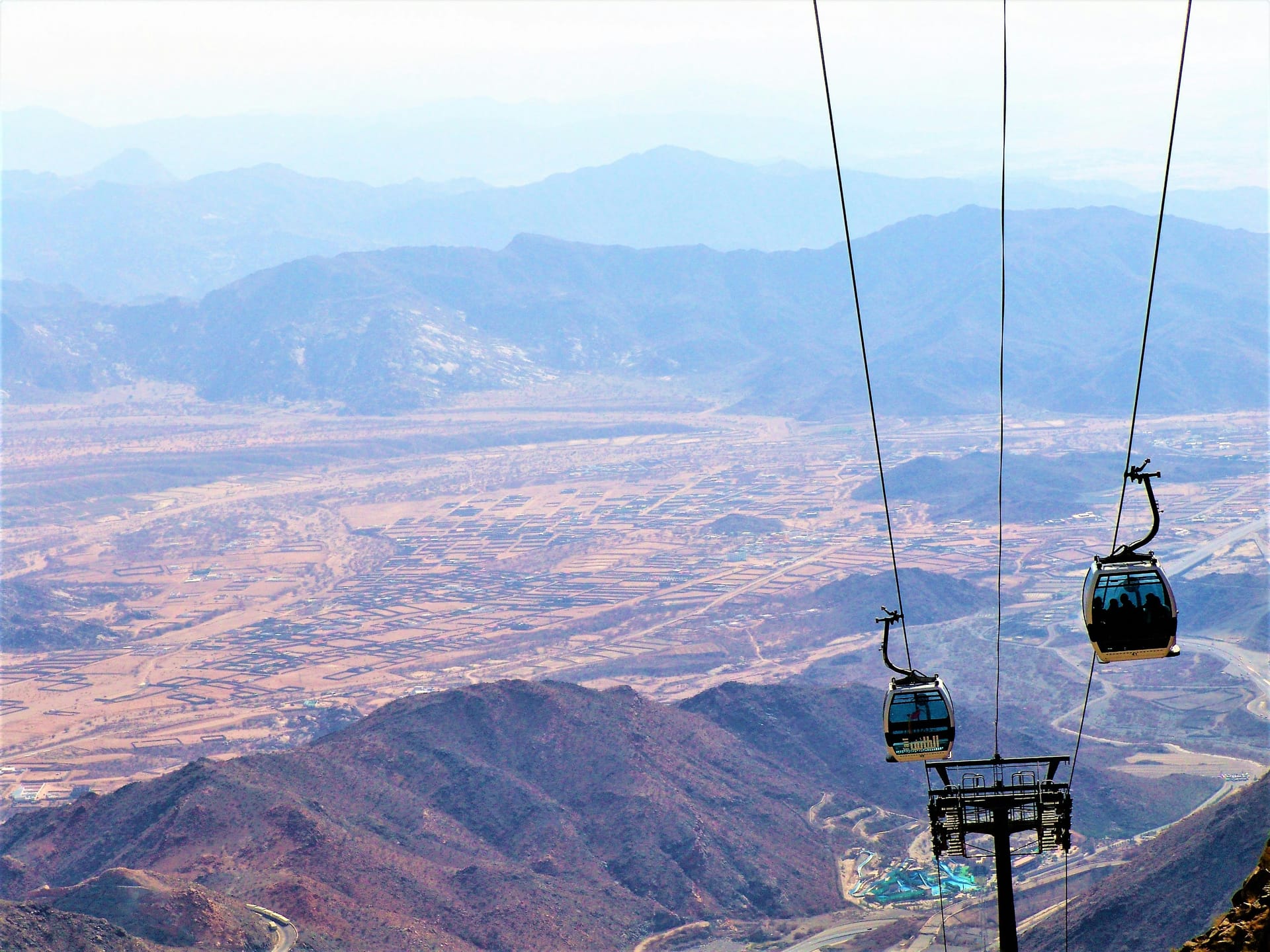 Cable cars suspended on wires moving over the steep, rocky mountain slopes of the Al Hada region in Taif.